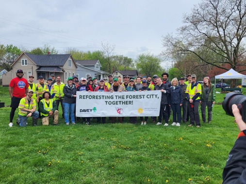 A group photo of volunteers at Cleveland park holding a sign that says, "Reforest the forest city, together"